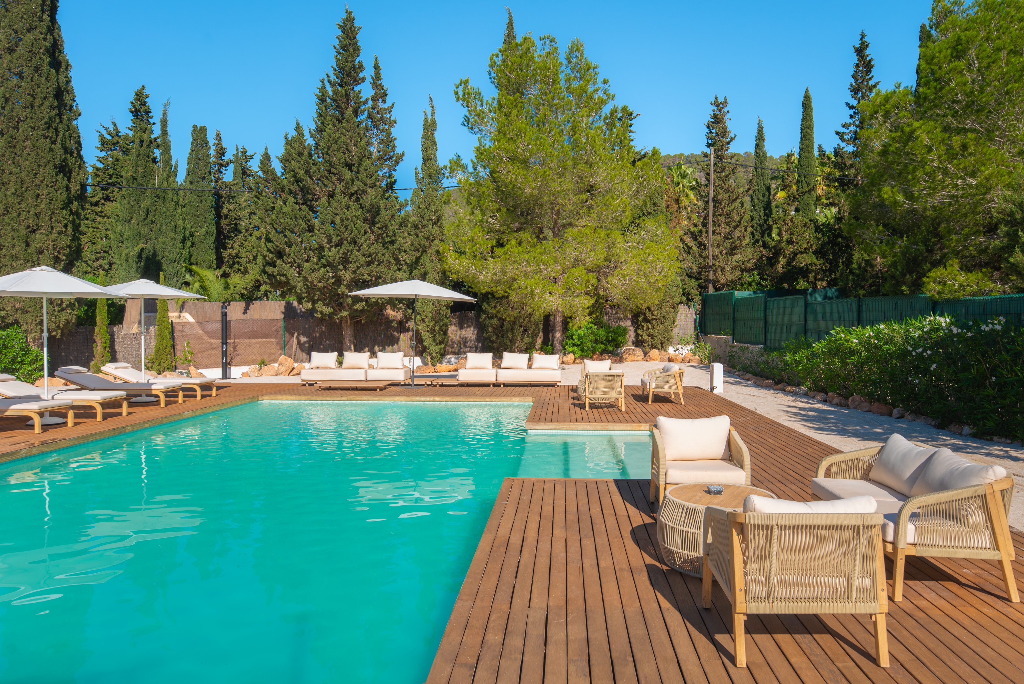 Villa Jondal 250 m² beach-club pool area with wooden deck and cypress trees — luxury villa near Cala Jondal Ibiza